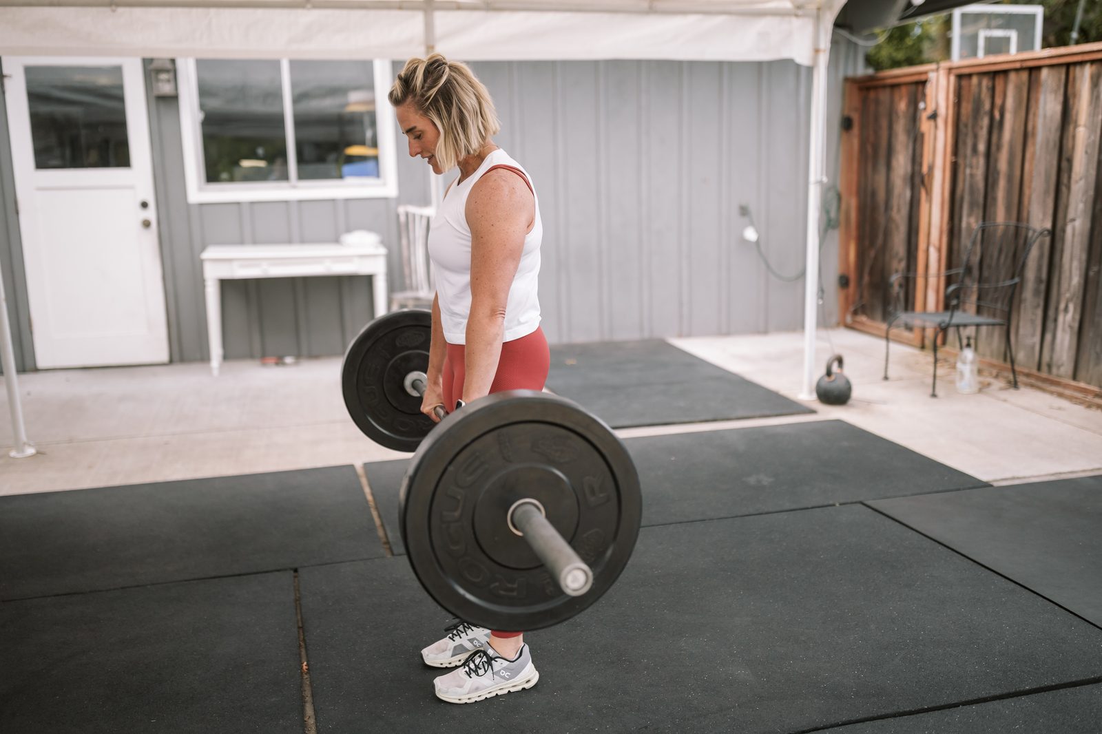Kristin setting up a barbell deadlift in her garage gym