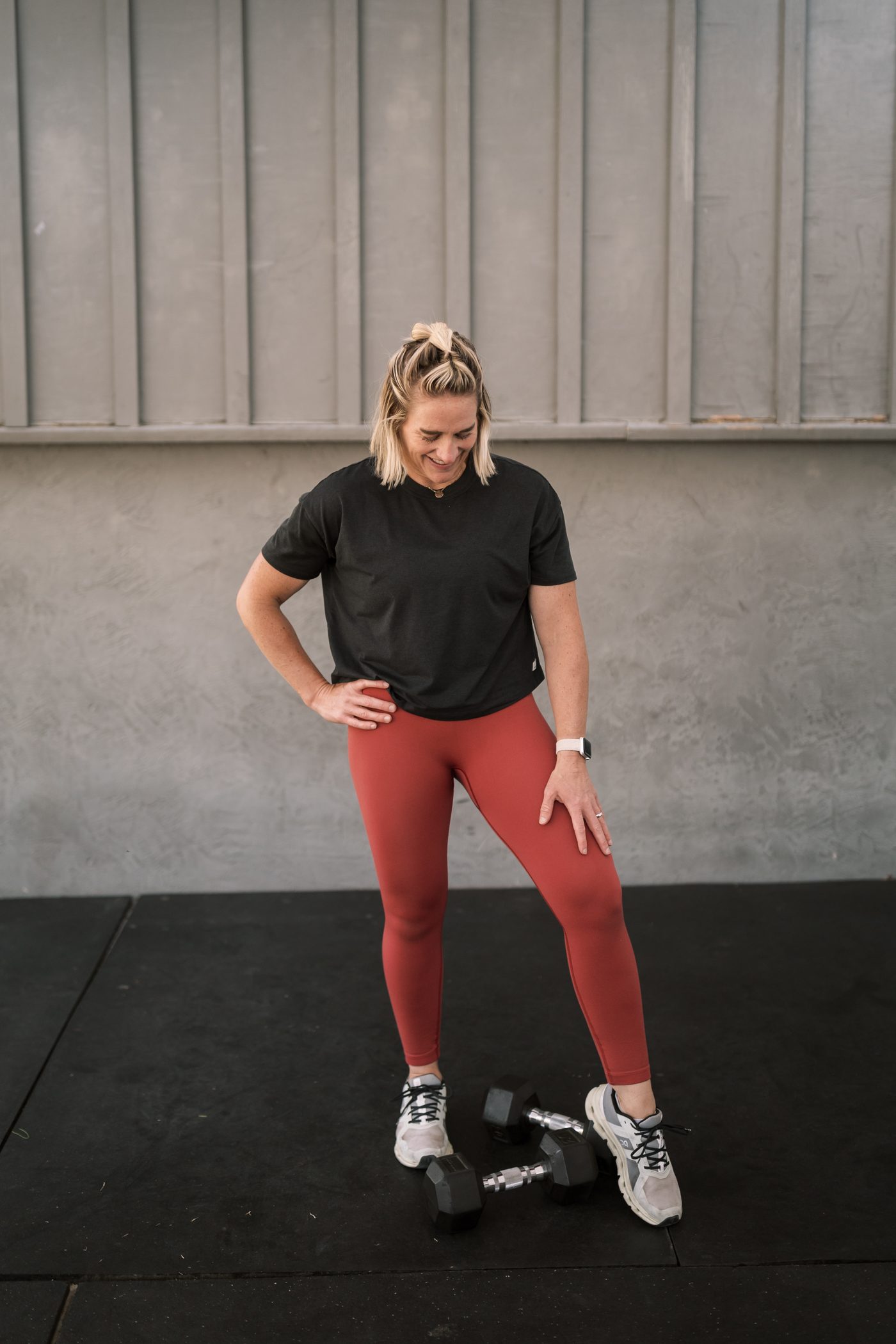 Kristin Wise standing in her gym with a dumbbell at her feet